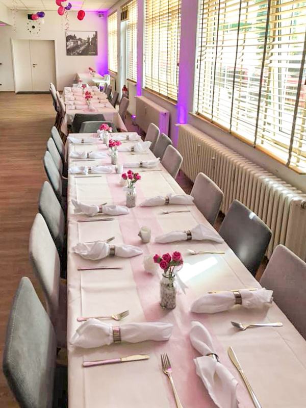 Lang gedeckte Festtafel mit Blumendeko im Tageslicht